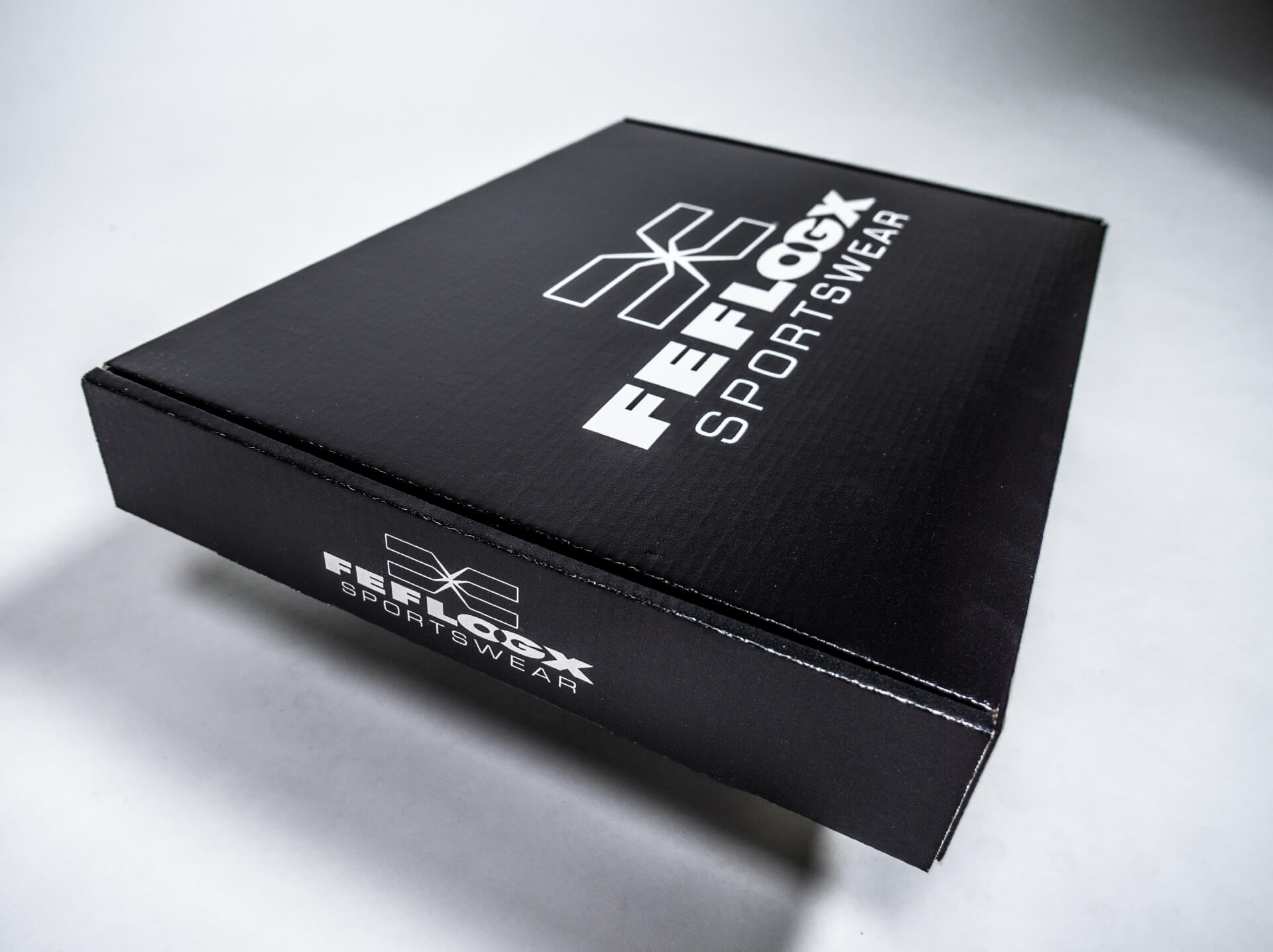 FEFLOGX Sportswear Versand-Karton, schwarz mit Logo (1), Fotoalbum.