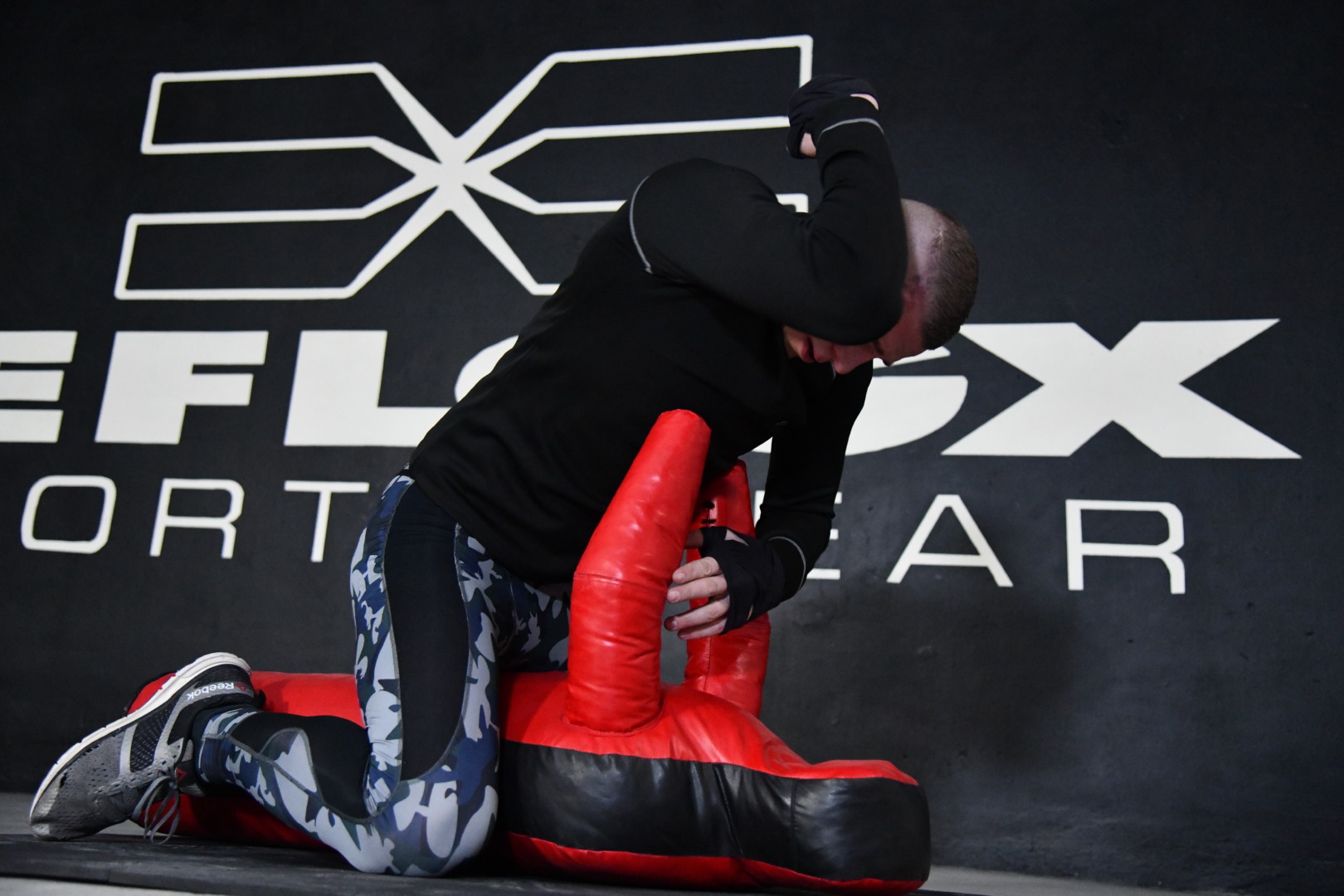 FEFLOGX, MMA-Training & Urban Functional Fitness Shooting in FFX Sport Leggings Camouflage, FFX Sport Shorts, FFX Boxbandagen & Sport Sweater, Fitness Longsleeve mit Kampfsport Dummy & Sport Reifen mit Hammer schlagen, Ground and Pound Ellenbogen zum Kopf, KO Ellenbogen Schlag Kickboxen in Industrie Ruine in Frankfurt am Main, mit FEFLOGX Logo-Graffiti an der Wand (7).