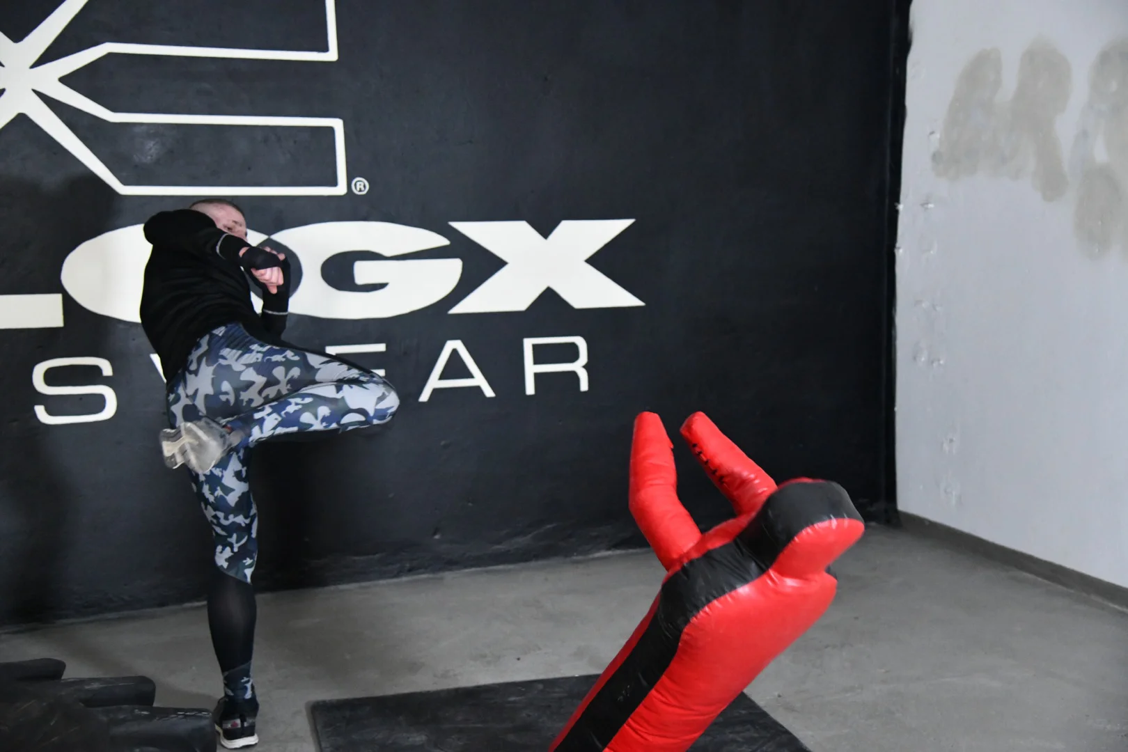 FEFLOGX, MMA-Training & Urban Functional Fitness Shooting in FFX Sport Leggings Camouflage, FFX Sport Shorts, FFX Boxbandagen & Sport Sweater, Fitness Longsleeve mit Kampfsport Dummy & Sport Reifen mit Hammer schlagen, Side-Kick / Round-House-Kick zum Kopf, KO-Tritt Kickboxen in Industrie Ruine in Frankfurt am Main, mit FEFLOGX Logo-Graffiti an der Wand (5).